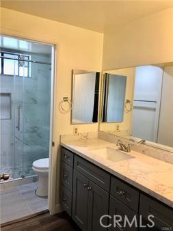 bathroom featuring hardwood / wood-style floors, vanity, toilet, and a shower with door