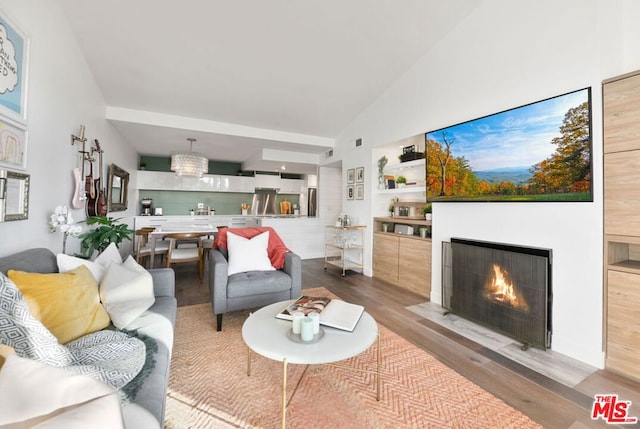 living room featuring high vaulted ceiling, light hardwood / wood-style floors, and an inviting chandelier