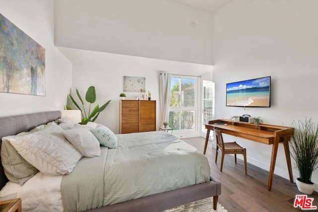 bedroom featuring hardwood / wood-style floors and a towering ceiling