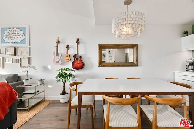 dining area featuring hardwood / wood-style floors, vaulted ceiling, and a notable chandelier