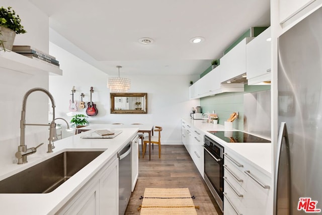 kitchen featuring pendant lighting, sink, dark hardwood / wood-style floors, appliances with stainless steel finishes, and white cabinetry