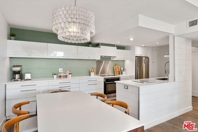 kitchen with sink, white cabinets, stainless steel appliances, and light hardwood / wood-style floors