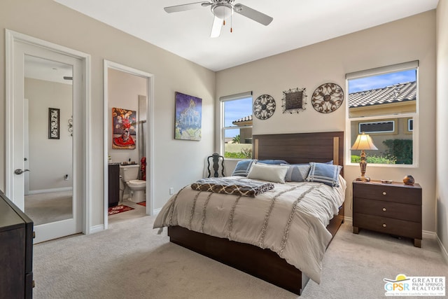 bedroom featuring ceiling fan, light carpet, and ensuite bath