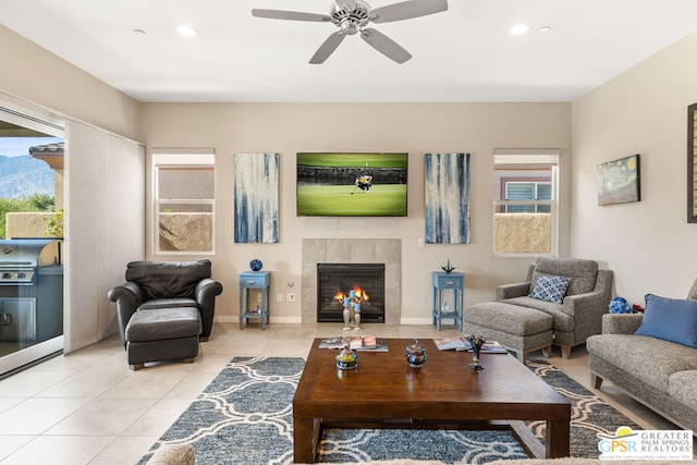 living room featuring ceiling fan, light tile patterned floors, and a tiled fireplace