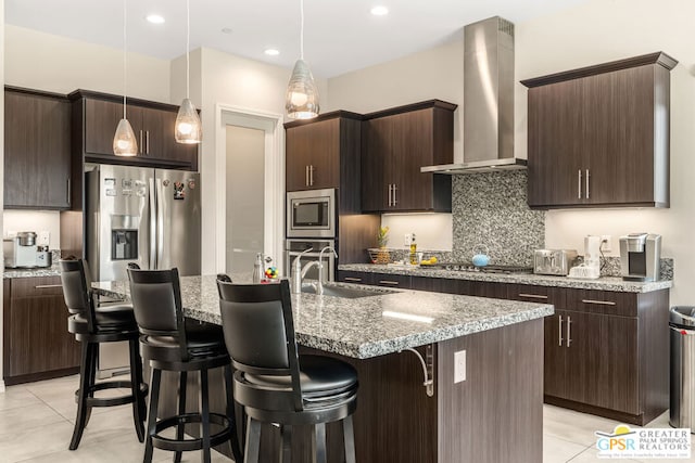 kitchen featuring dark brown cabinetry, an island with sink, and hanging light fixtures