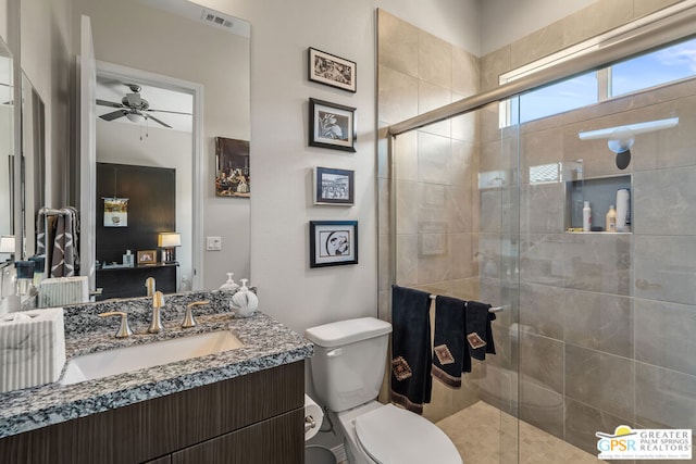 bathroom with ceiling fan, vanity, a shower with shower door, and toilet