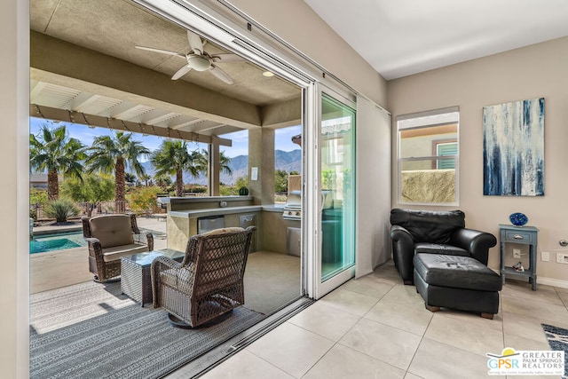 doorway featuring a mountain view, ceiling fan, and light tile patterned floors