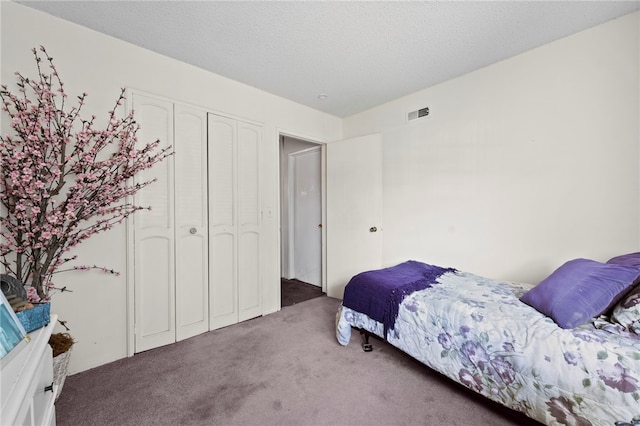 carpeted bedroom featuring a textured ceiling and a closet