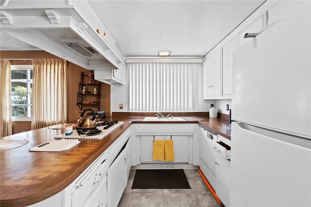 kitchen featuring sink, white cabinets, wooden counters, and white appliances