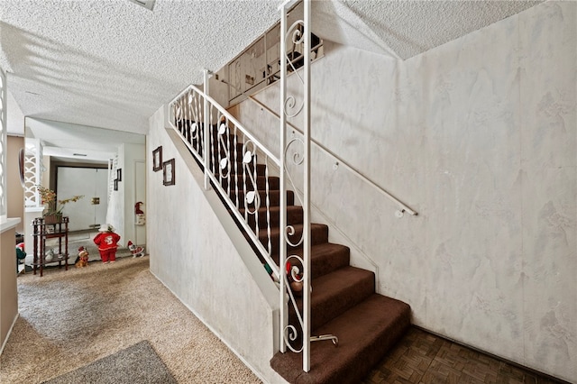 staircase with parquet flooring and a textured ceiling