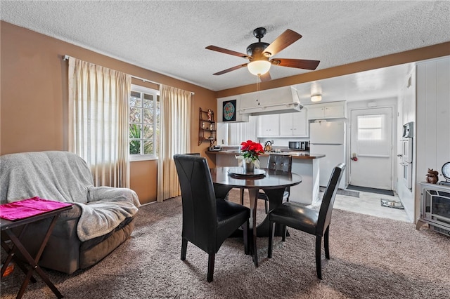 dining room with ceiling fan, light colored carpet, and a textured ceiling