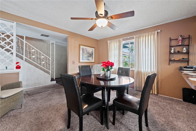 dining room featuring carpet, ceiling fan, and a textured ceiling