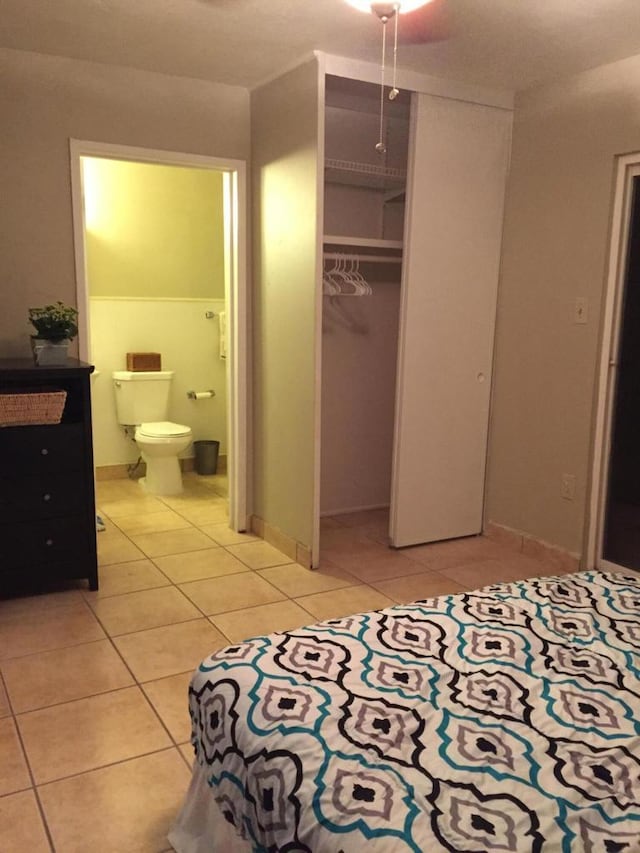 bedroom with ensuite bathroom, light tile patterned floors, and a closet