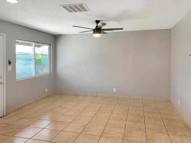 empty room with ceiling fan and light tile patterned floors