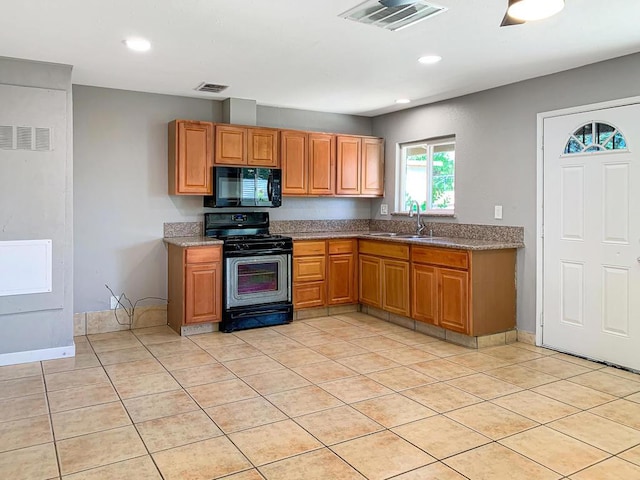 kitchen featuring black appliances, light tile patterned floors, and sink