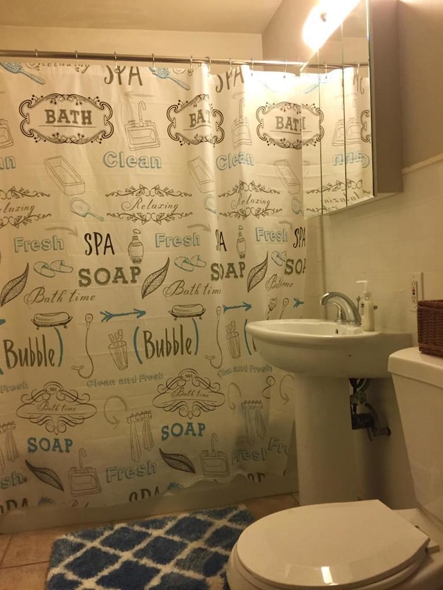 bathroom featuring tile patterned flooring, backsplash, toilet, and walk in shower