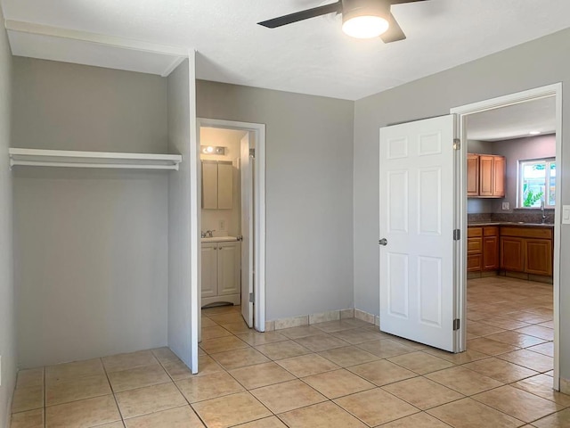 unfurnished bedroom with ensuite bathroom, ceiling fan, and light tile patterned flooring