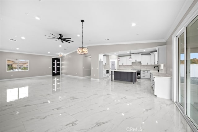 unfurnished living room featuring ceiling fan with notable chandelier, ornamental molding, and sink