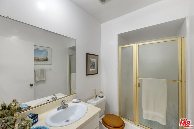 bathroom with vanity, toilet, and a shower with shower door