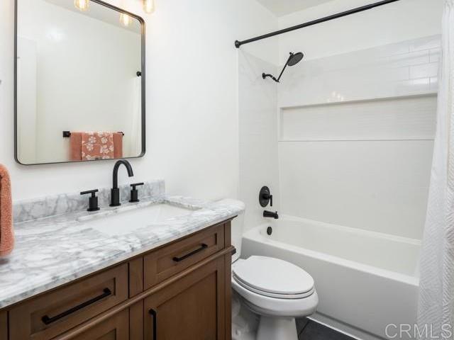 full bathroom with shower / tub combo with curtain, vanity, and toilet