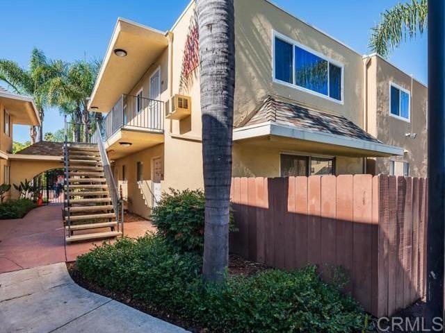 view of side of home featuring stairway, stucco siding, and fence