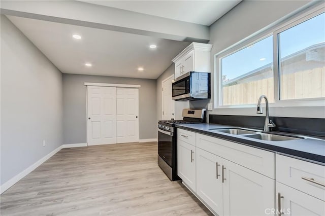 kitchen with appliances with stainless steel finishes, light wood-type flooring, white cabinetry, and sink