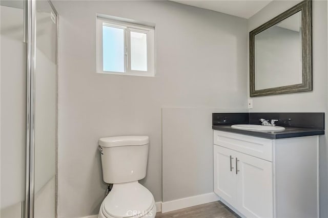 bathroom featuring toilet, vanity, a shower with door, and hardwood / wood-style flooring