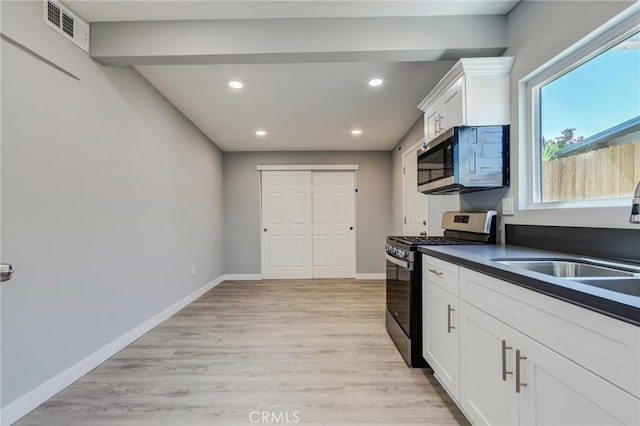 kitchen with sink, white cabinetry, stainless steel appliances, and light hardwood / wood-style flooring