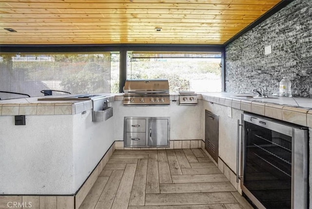 view of patio with sink, beverage cooler, an outdoor kitchen, and grilling area