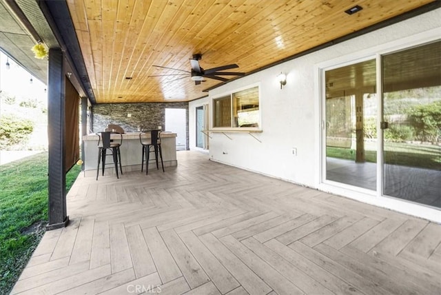 wooden terrace featuring ceiling fan and a bar