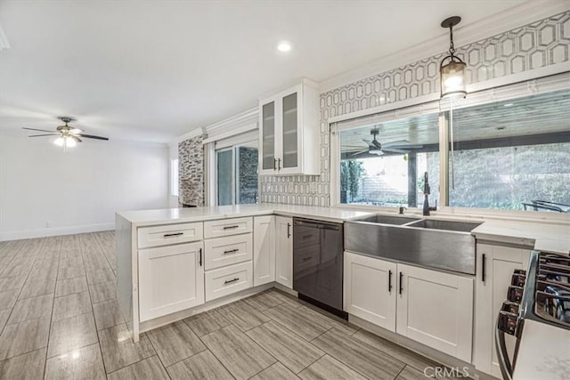 kitchen featuring dishwasher, stove, sink, hanging light fixtures, and white cabinets