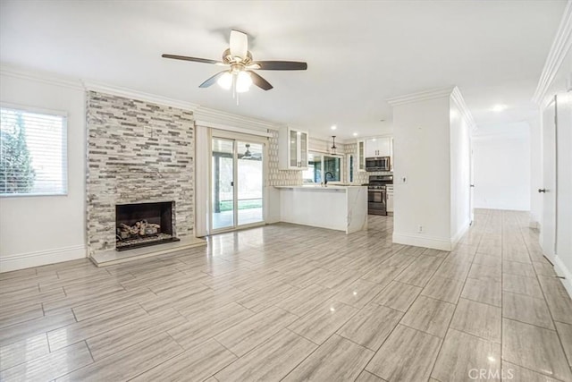 unfurnished living room with ceiling fan, a fireplace, sink, and ornamental molding