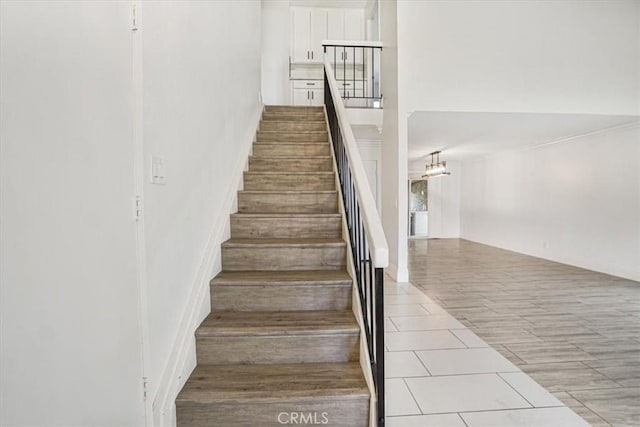 stairs with ornamental molding and tile patterned floors