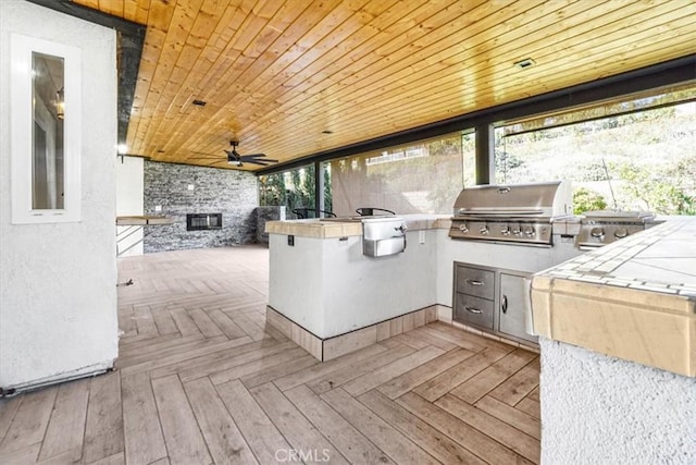 wooden deck with grilling area, ceiling fan, and an outdoor kitchen