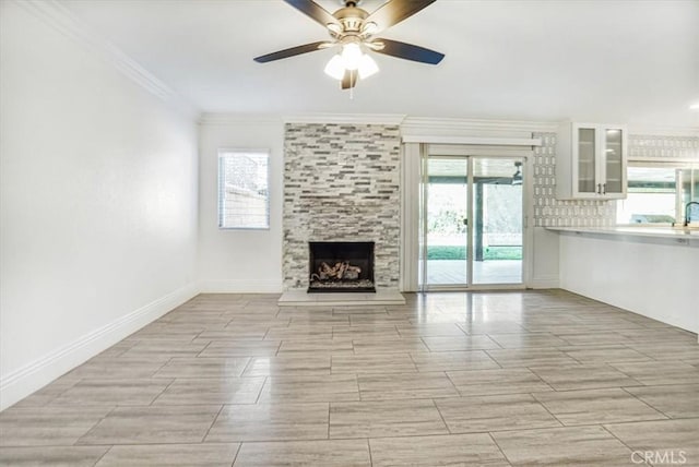 unfurnished living room with ceiling fan, crown molding, and a fireplace