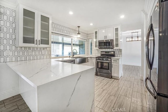 kitchen featuring kitchen peninsula, appliances with stainless steel finishes, hanging light fixtures, light stone countertops, and white cabinets