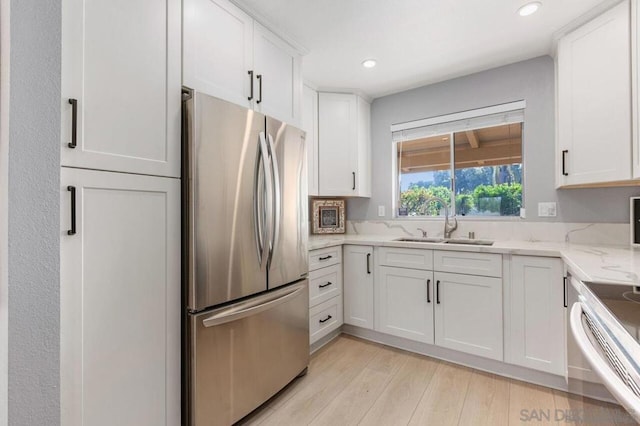 kitchen with white cabinetry, light hardwood / wood-style flooring, light stone counters, and appliances with stainless steel finishes