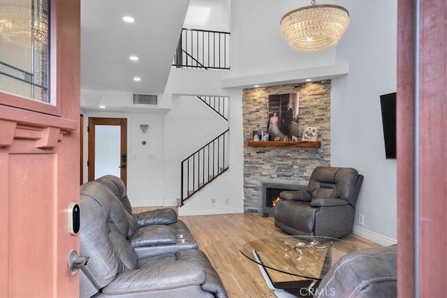 living room featuring hardwood / wood-style floors, a stone fireplace, and a chandelier