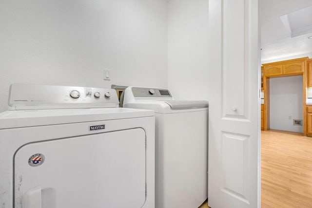 laundry room with separate washer and dryer and light hardwood / wood-style flooring