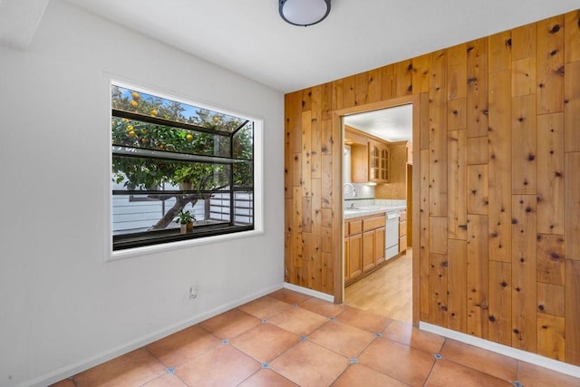 tiled spare room featuring wooden walls and sink