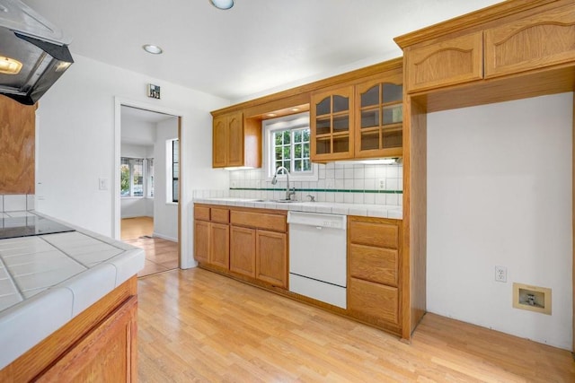 kitchen with sink, dishwasher, backsplash, range hood, and tile countertops