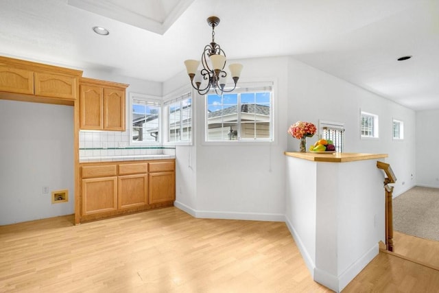 kitchen with pendant lighting, tile countertops, decorative backsplash, a notable chandelier, and light hardwood / wood-style floors