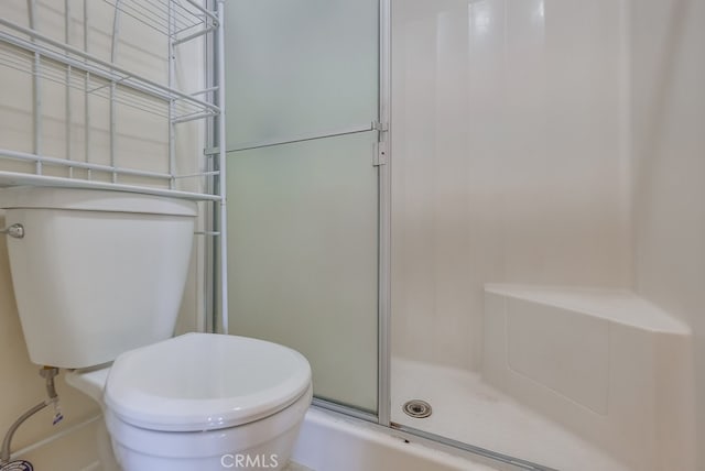 bathroom with a shower with door and toilet