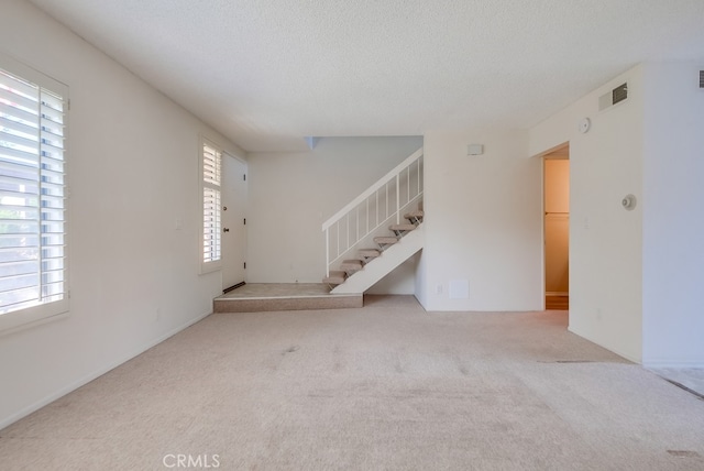 unfurnished living room with light carpet and a textured ceiling