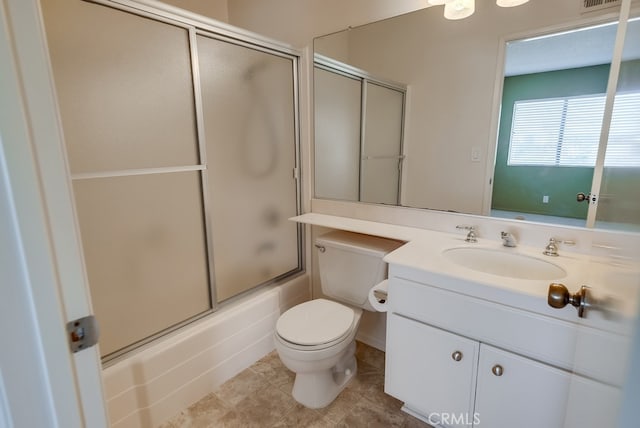 full bathroom featuring vanity, tile patterned flooring, bath / shower combo with glass door, and toilet