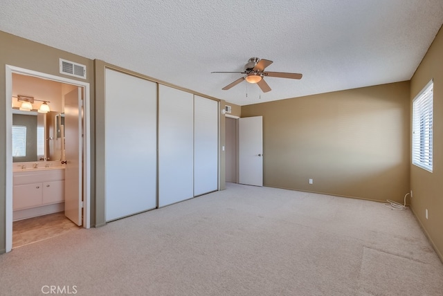 unfurnished bedroom with light carpet, a closet, and a textured ceiling