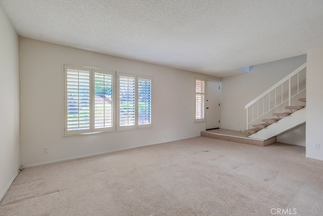 unfurnished living room featuring light carpet and a textured ceiling