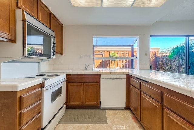 kitchen featuring sink, tile countertops, white appliances, and kitchen peninsula