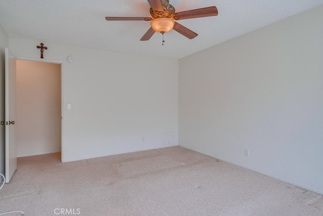 spare room featuring ceiling fan, light carpet, and a textured ceiling