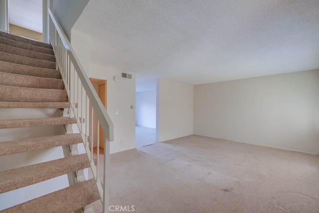 staircase with a textured ceiling and carpet